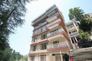 a tall building with white balconies and trees at Decent Stays in Shimla +9 photos