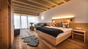 ein Schlafzimmer mit einem großen Bett und einem Sofa in der Unterkunft Hotel Moritz in Toblach