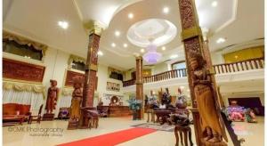 una grande hall con colonne e tavoli in legno e un lampadario a braccio di Vy Chhe Hotel a Battambang