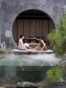 twee mensen zitten aan een tafel naast een waterpoel bij 大理古城归渊民宿 in Dali (oude stad)
