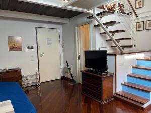 a living room with a television and a staircase at Ariston Luxury Apartment in Sanremo