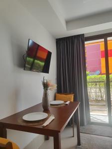 a dining room table with a television on a wall at Уютная студия в жилом комплексе в заповедном уголке Пхукета in Ban Mai Salae