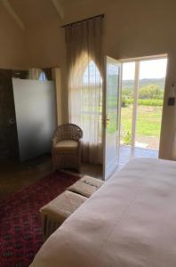 - une chambre avec un lit, une chaise et une porte dans l'établissement The Schoolhouse at Meulplaas, à Montagu