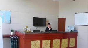 a woman is sitting at a reception desk at GreenTree Inn Weihai Port in Weihai