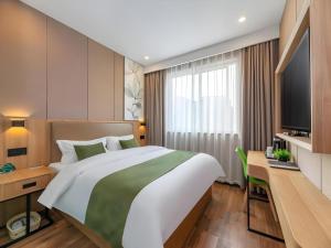 a bedroom with a large bed and a desk and a television at GreenTree Inn Jining Jianshe Road Hotel in Jining +76 photos