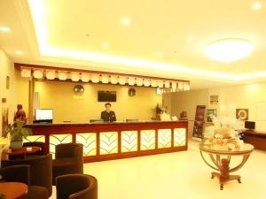 a woman standing at a counter in a lobby at GreenTree Inn Yangzhou South Yunhe Road Yangzhou Bridge Express Hotel in Yangzhou