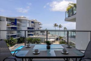 Luxury 2 Bedroom Apartment Beach Views Pool في Urangan: شرفة مع طاولة وإطلالة على المحيط