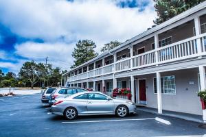 a row of cars parked in a parking lot next to a building at Pelican Inn in Monterey