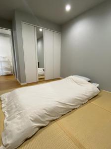 a bedroom with a large white bed with a mirror at 簡易宿所　ふくろく in Shingu
