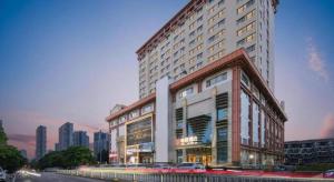 un grande edificio con auto parcheggiate di fronte di Echeng Hotel Wuhan Optics Valley Square Yangjiawan Metro Station a Wuhan