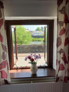 a vase with flowers sitting on a window sill at Character Cottage in Usk in Usk +6 photos