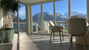 a room with two chairs and a view of mountains at Venez Chez Vous Villa Aux Premières Loges in Sévrier