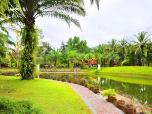 a park with a pond and palm trees and a path at Phatad Valley Hotel in Ban Kui Mang