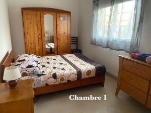 a bedroom with a bed and a dresser and a mirror at Appart Cozy Ivandry dans villa in Antananarivo