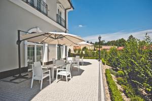 a patio with a table and chairs and an umbrella at Hotel Toscania in Włoszakowice