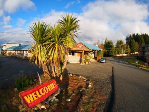 una señal de bienvenida frente a una casa con una palmera en West Coast Motel on the Harbour, en Ucluelet