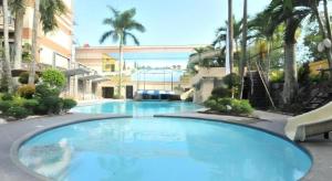 a large blue swimming pool in a building with palm trees at Queen Margarette Hotel in Lucena