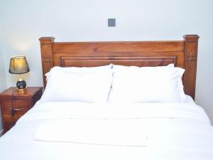 a white bed with a wooden headboard and a lamp at DeeHomes in Eldoret