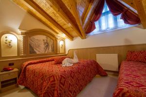 a bedroom with two beds with a cat laying on the bed at Hotel Orchidea in Passo del Tonale