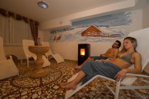 a man and a woman sitting in chairs in a room at Hotel Orchidea in Passo del Tonale