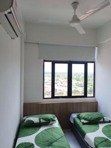 two beds in a room with a window at Alor Setar Imperio by IM Staycation 3bedroom & Rooftop Pool in Alor Setar