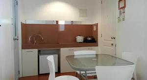 a kitchen with a glass table and white chairs at House of Big Brother in Puerto Princesa City