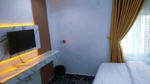 a hotel room with a bed and a flat screen tv at Jade Luxe 2 Bedroom Apartment in Agbor