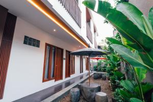 an outdoor patio with an umbrella and some plants at Royal Sweet By Sika in Canggu