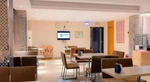 a waiting room with tables and chairs and a tv at City Comfort Inn Guigang Tangren Street in Guigang