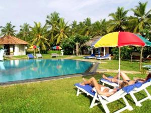 un gruppo di persone sdraiate su sedie a sdraio a bordo piscina di Aquarius Resort a Marawila
