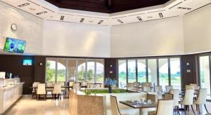 a dining room with tables and chairs and windows at Sono Belle Haiphong in Hai Phong