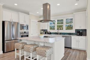 a kitchen with white cabinets and a large island with bar stools at Blue Heaven Villa in Tybee Island
