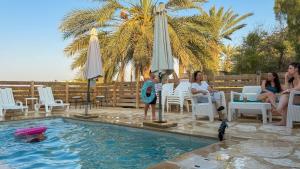 a group of people sitting around a swimming pool at סוף העולם שמאלה in Idan