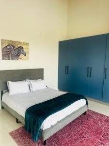 a bedroom with a bed with blue cabinets and a rug at Duinen Suites in Walvis Bay
