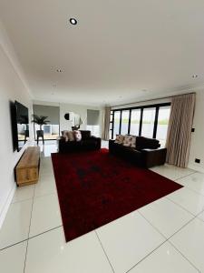 a living room with two couches and a red rug at Duinen Suites in Walvis Bay +18 photos