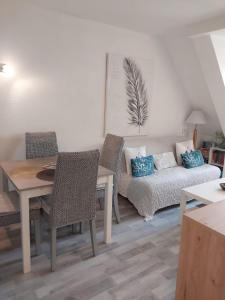 a living room with a couch and a table and chairs at Cosy appartement dans une villa avec piscine, proche du centre et de la mer in Cabourg