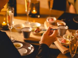 a person sitting at a table with a plate of food at Glamday style hotel suite 川ノ音 in Kyū-karuisawa