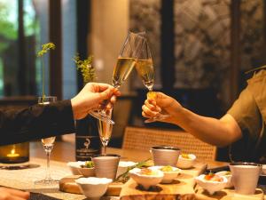 two people holding champagne glasses at a table at Glamday style hotel suite 川ノ音 in Kyū-karuisawa