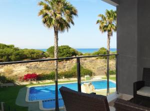 a balcony with a view of a swimming pool and palm trees at Pinada La Mata in La Mata