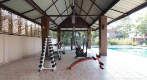 - une salle de sport avec des équipements d'exercice dans un pavillon à côté d'une piscine dans l'établissement Tong House Resort, à Chiang Mai