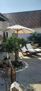 une terrasse avec un parasol, des chaises et un arbre dans l'établissement Wohnen & Schlafen im Cottage, à Wundschuh