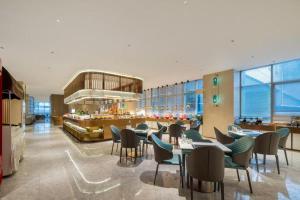 a restaurant with tables and chairs and a bar at New Century Hotel Nanjing in Nanjing