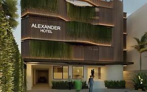 Una mujer está parada frente a un hotel. en Alexander Hotel Tegal, en Tegal