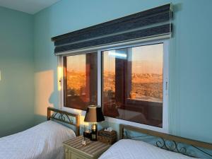 a bedroom with two beds and a large window at Al-Bustan House& Umm Qais in Um Qeis