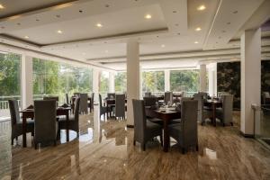 Un comedor con mesas y sillas y ventanas. en Praia Bay Hiriketiya, en Hiriketiya