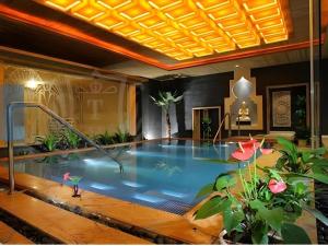 a large swimming pool in a room with plants at New Century Grand Hotel Zhuji Yaojiang in Shaoxing