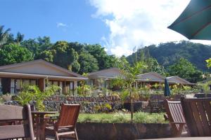 a restaurant with wooden tables and chairs and trees at Le Manumea Hotel in Apia