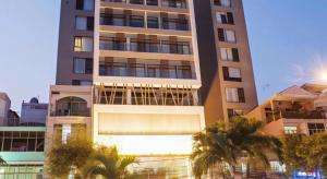a tall building with palm trees in front of it at Iris Hotel Can Tho in Can Tho