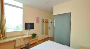 a bedroom with a bed and a desk and a tv at 7 Days Inn Zibo Linzi District Tianqi Road Qina Studio in Zibo +11 photos