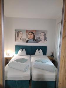 Dos camas en una habitación con retratos en la pared. en Centar Novi Sad-Apartman No 1 PARKING ON REQUEST, en Novi Sad